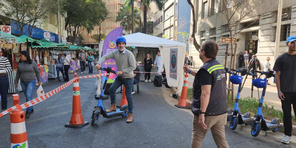 Participante testa patinete elétrico durante atividade da "Escola de Direção Segura de Patinetes" no centro de BH, com capacete obrigatório e orientações de monitores (Maurício Vieira/Hoje em Dia)