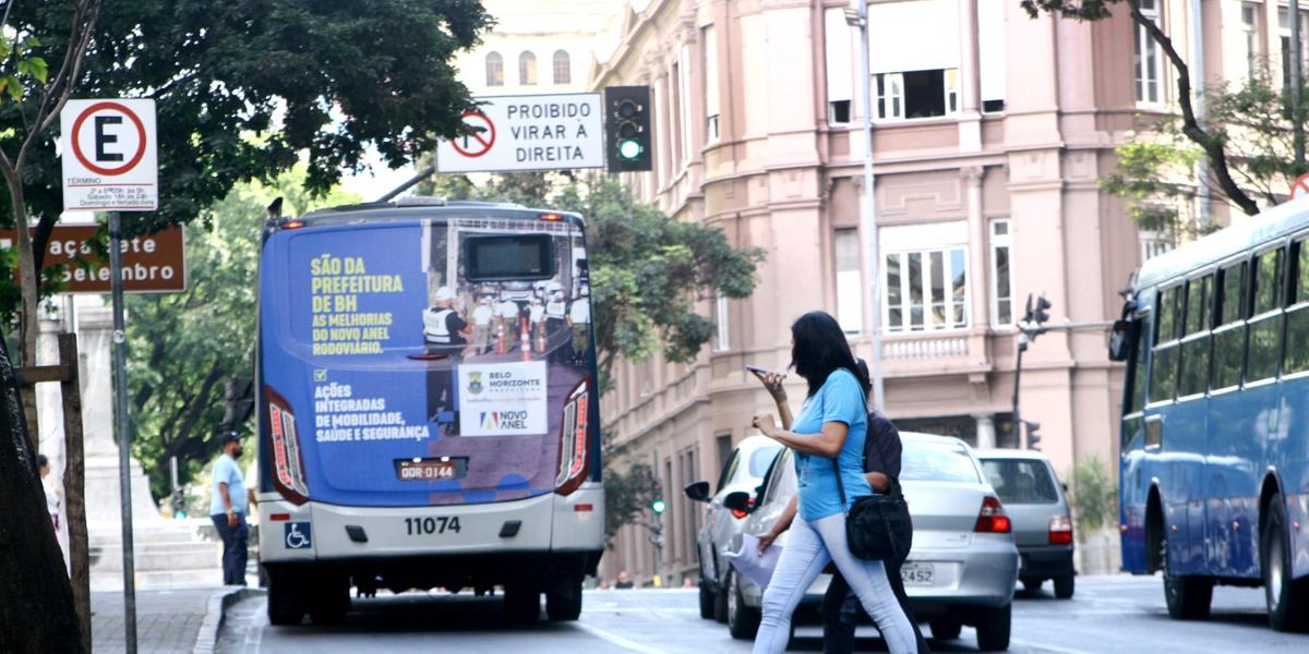 Pedestre se arrisca atravessando fora da faixa, com o sinal aberto para os carros e usando o celular na Praça 7, no Centro de BH (Maurício Vieira)