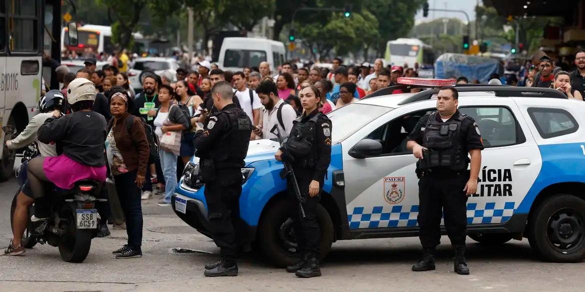 Agentes da polícia fazem guarda perto de filas nos pontos de ônibus e vans de transporte (Fernando Frazão/Agência Brasil)