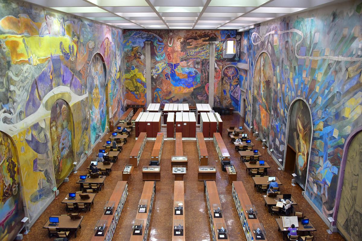 A monumental sala de leitura da Biblioteca Miguel Lerdo de Tejada, no Centro Histórico, cercada por murais de Vlady. O espaço abriga um dos acervos mais importantes do país, especialmente dedicado à economia e à memória cultural mexicana (Gobierno de Mexico)