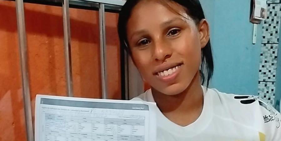 Gabriela sorri, aliviada, e mostra o cartão de vacina da pequena Larissa (Arquivo pessoal / Reprodução)